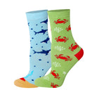 Two pairs of kids crew socks, one light blue with a dark blue shark pattern and one light green with a red crab pattern.