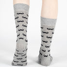 Gray socks with black mustache pattern worn by a person on a white background