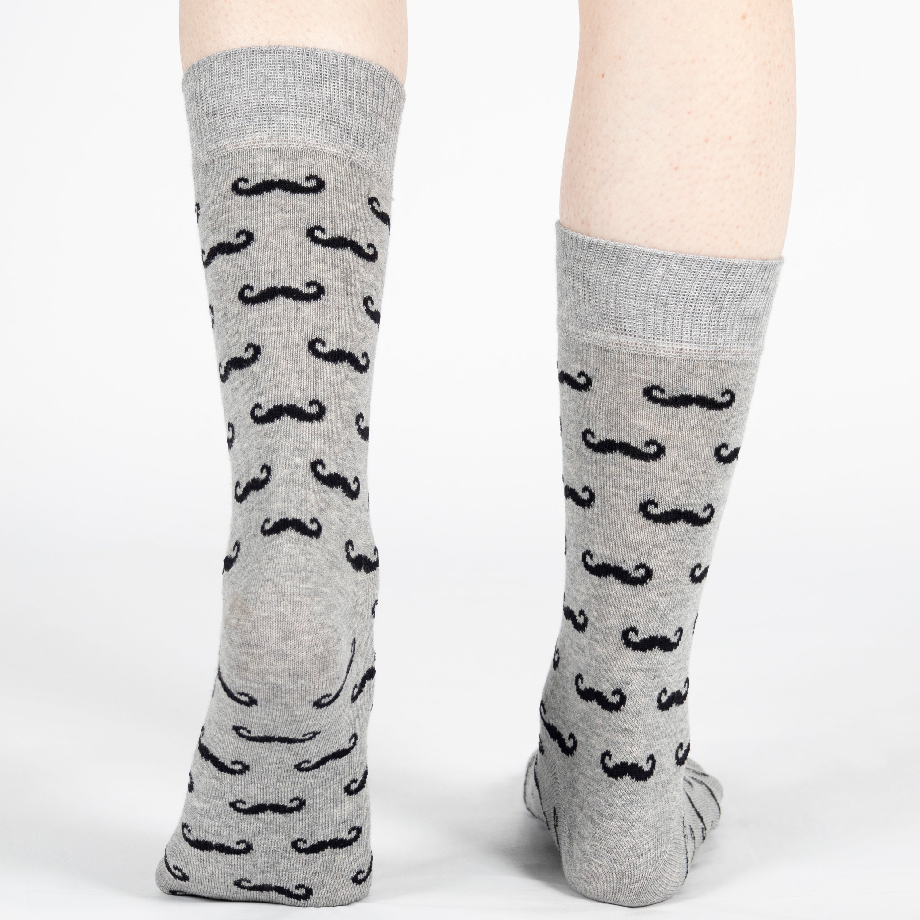Gray socks with black mustache pattern worn by a person on a white background