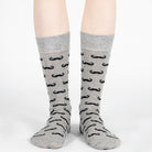 Gray socks with black mustache pattern worn by a person on a white background