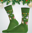 Green socks with penguin design on a white background with Christmas decorations.